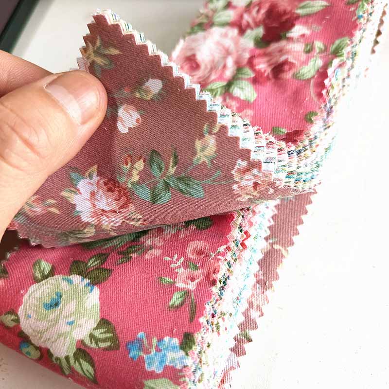 Floral fabric strips held by hand, showcasing vibrant rose and flower designs